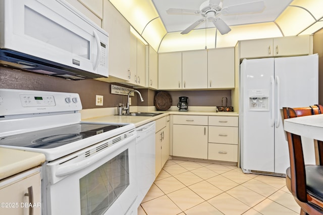 kitchen with sink, light tile patterned floors, white appliances, and cream cabinetry