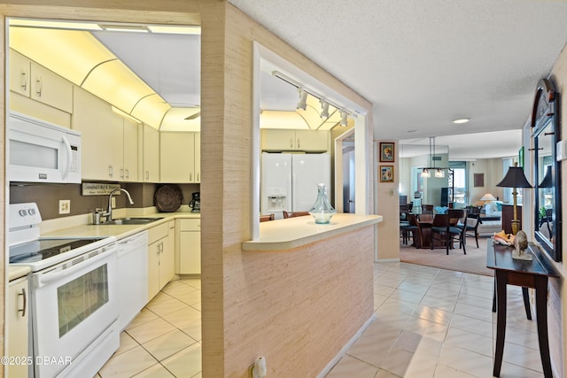 kitchen featuring light tile patterned flooring, a textured ceiling, white appliances, and sink