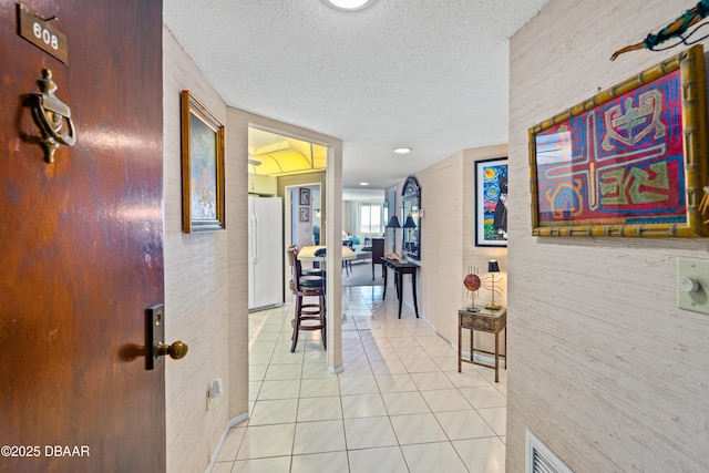 hall featuring light tile patterned flooring and a textured ceiling