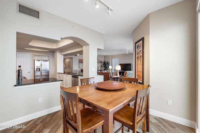 3737 S Atlantic Ave Unit 702, Daytona Beach, FL 32118 - dining area with wood finished floors, track lighting, ceiling fan, and arched walkways