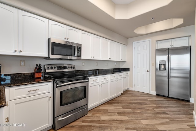 3737 S Atlantic Ave Unit 702, Daytona Beach, FL 32118 - kitchen featuring appliances with stainless steel finishes, light wood finished floors, white cabinetry, and dark stone countertops