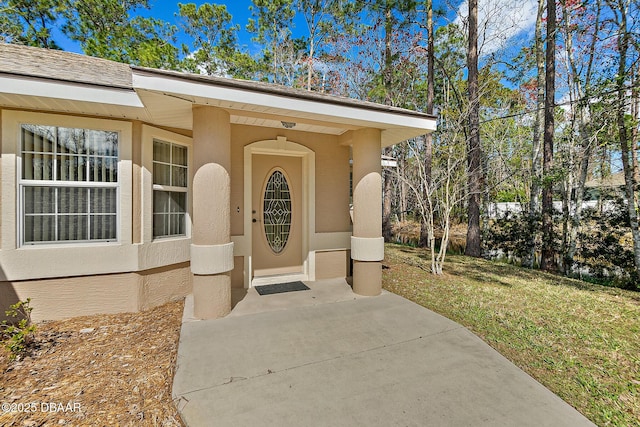 doorway to property featuring a yard and stucco siding