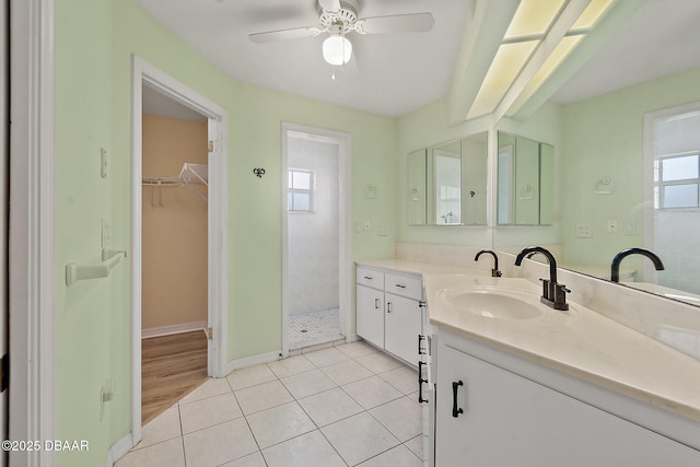 full bath with a ceiling fan, tile patterned flooring, tiled shower, a spacious closet, and vanity