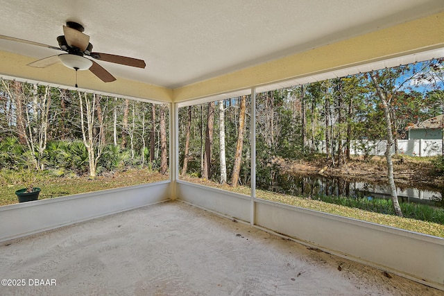 unfurnished sunroom with a ceiling fan and a water view