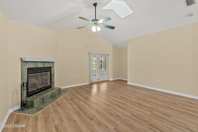 unfurnished living room featuring visible vents, baseboards, ceiling fan, a tiled fireplace, and wood finished floors