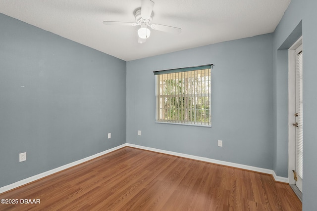 empty room with ceiling fan, baseboards, and wood finished floors