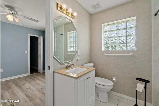 bathroom with visible vents, toilet, baseboards, ceiling fan, and vanity