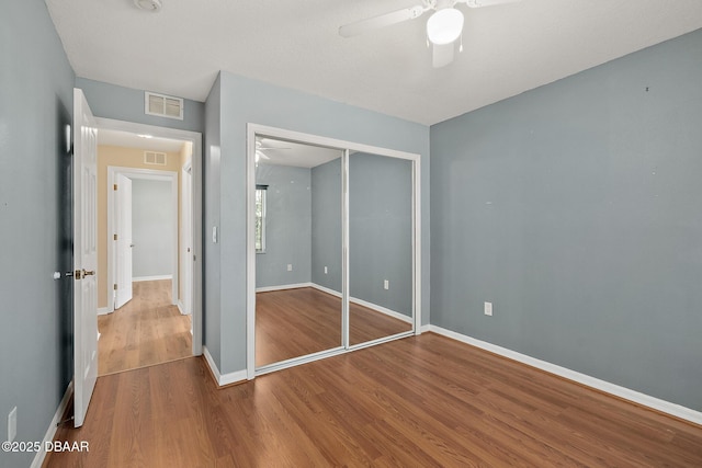 unfurnished bedroom with visible vents, baseboards, a closet, and wood finished floors