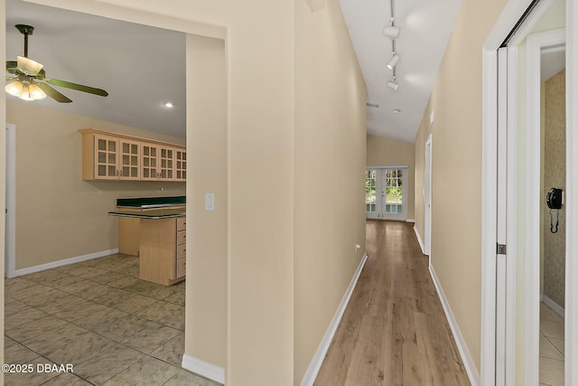 hall with track lighting, french doors, baseboards, and lofted ceiling