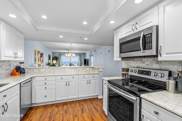 3333 S Atlantic Ave Unit 1802, Daytona Beach, FL 32118 - kitchen featuring stainless steel appliances, a tray ceiling, dark wood-style flooring, tasteful backsplash, and a peninsula