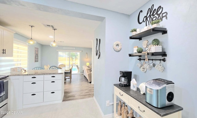 8 Tarpon Ave, Ormond Beach, FL 32176 - kitchen with white cabinets, baseboards, hanging light fixtures, open shelves, and a peninsula