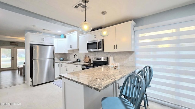 8 Tarpon Ave, Ormond Beach, FL 32176 - kitchen with appliances with stainless steel finishes, a sink, light stone counters, and white cabinetry