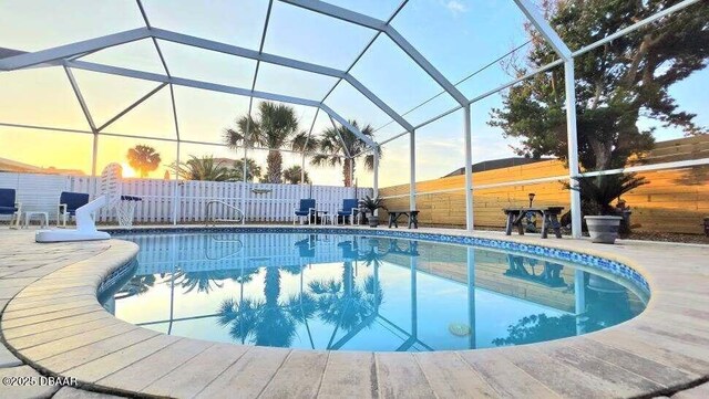 8 Tarpon Ave, Ormond Beach, FL 32176 - pool at dusk with fence, a patio, and glass enclosure