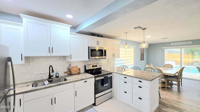 8 Tarpon Ave, Ormond Beach, FL 32176 - kitchen with stainless steel appliances, a peninsula, a sink, tasteful backsplash, and recessed lighting