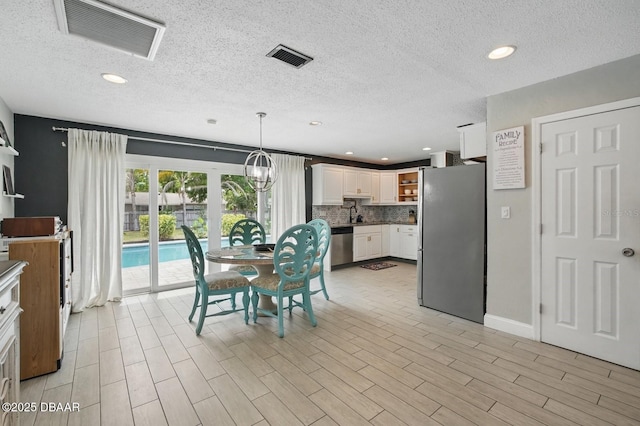 dining room with a textured ceiling, recessed lighting, light wood finished floors, and baseboards