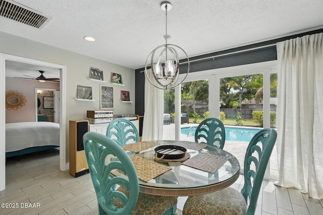 dining space with light wood-type flooring, a textured ceiling, a chandelier, recessed lighting, and a ceiling fan