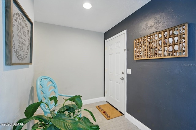 doorway to outside featuring baseboards and wood finished floors
