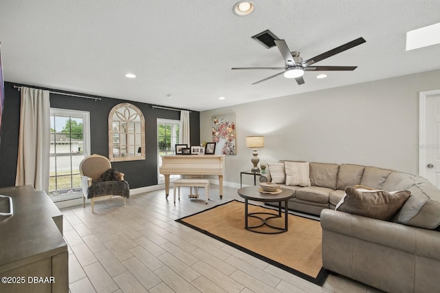 living room featuring a ceiling fan, baseboards, recessed lighting, and light wood-style flooring