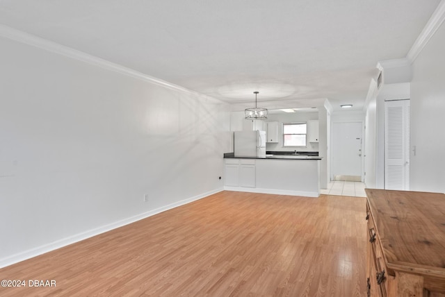 unfurnished living room featuring light hardwood / wood-style floors, crown molding, and a notable chandelier