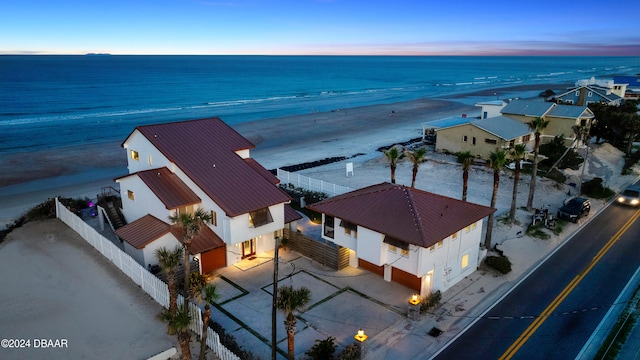 aerial view at dusk featuring a beach view and a water view