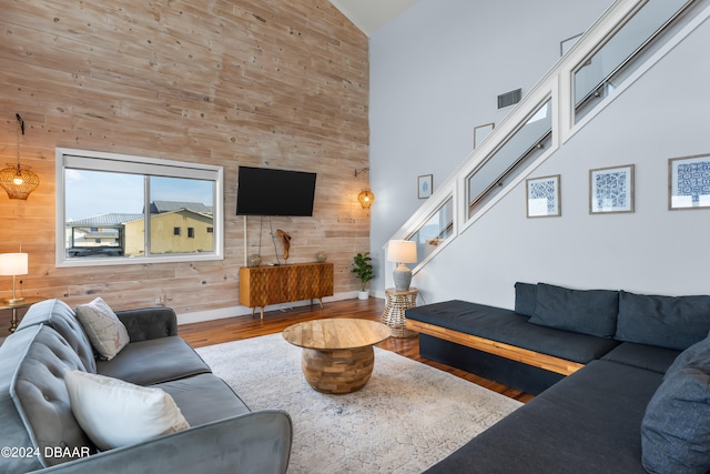 living room with high vaulted ceiling, hardwood / wood-style floors, and wooden walls