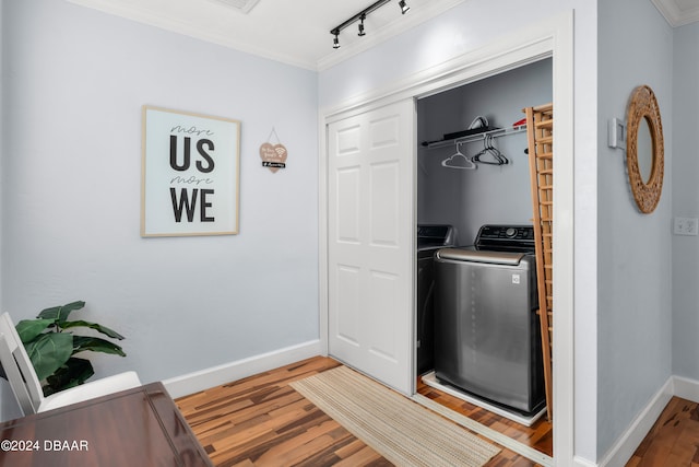 washroom with washing machine and dryer, track lighting, light hardwood / wood-style flooring, and ornamental molding