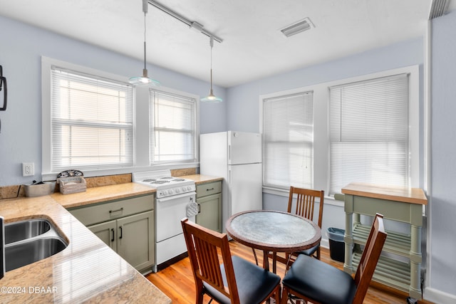 kitchen featuring track lighting, sink, light hardwood / wood-style flooring, white appliances, and decorative light fixtures