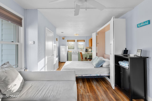 bedroom featuring hardwood / wood-style flooring, ceiling fan, and white fridge