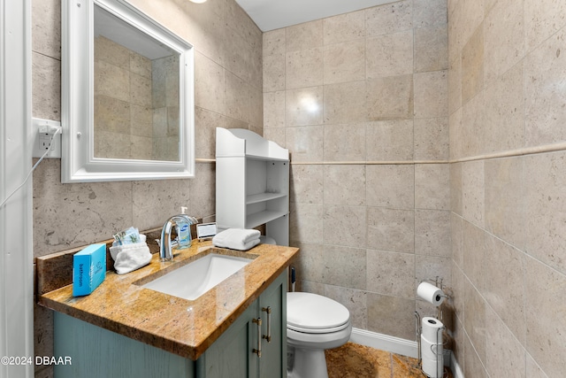 bathroom featuring vanity, toilet, and tile walls