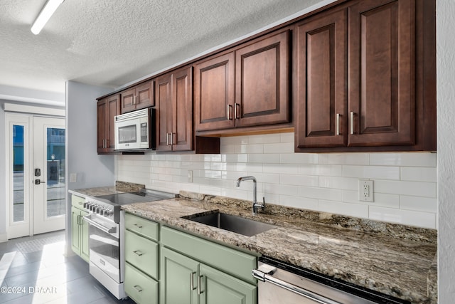 kitchen featuring green cabinets, sink, appliances with stainless steel finishes, stone counters, and french doors