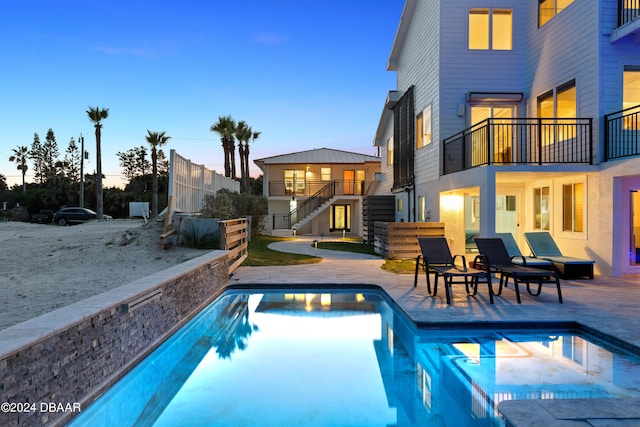 pool at dusk featuring a patio area