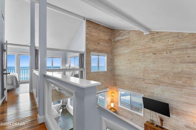 room details featuring wood walls, a water view, hardwood / wood-style flooring, and beam ceiling