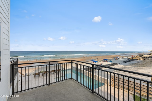 balcony featuring a view of the beach and a water view