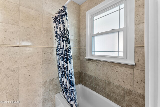 bathroom with a healthy amount of sunlight and shower / bath combo with shower curtain