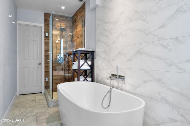 bathroom with tile walls and shower with separate bathtub