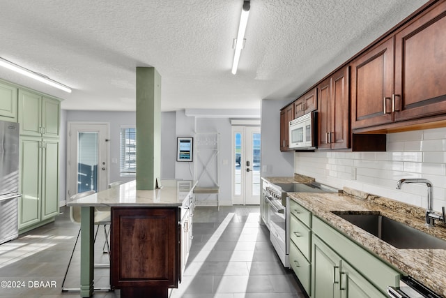 kitchen with green cabinets, stainless steel appliances, a textured ceiling, and sink