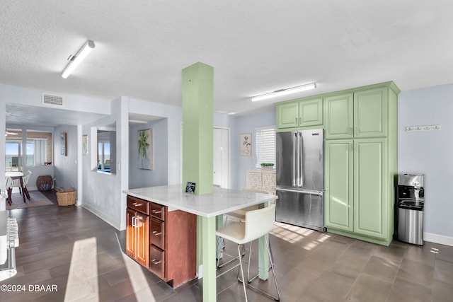 kitchen featuring light stone counters, a kitchen island, a textured ceiling, dark hardwood / wood-style flooring, and high end fridge