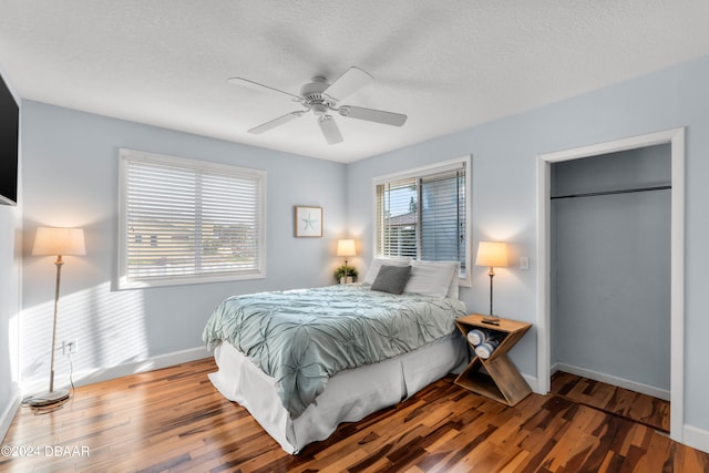 bedroom featuring hardwood / wood-style flooring, ceiling fan, multiple windows, and a textured ceiling