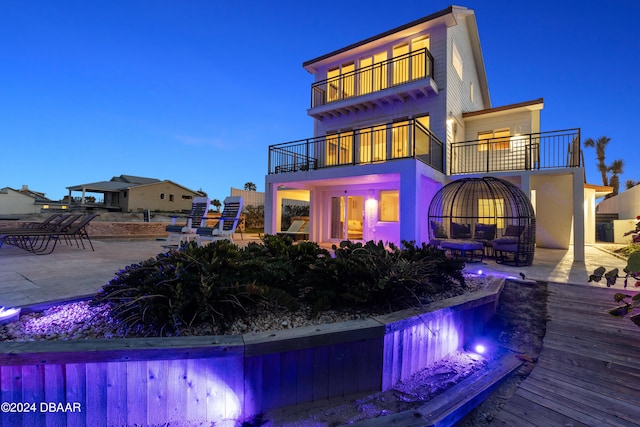 back house at dusk with a patio and a balcony