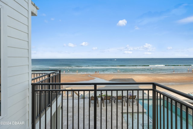 balcony with a water view and a view of the beach