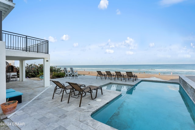 view of pool featuring a view of the beach, a water view, and a patio area