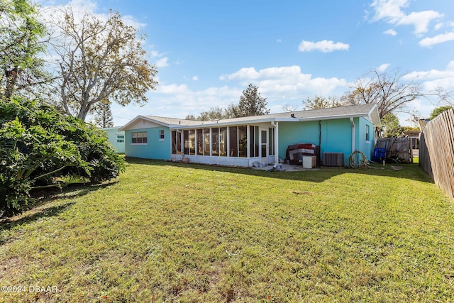 rear view of house featuring a sunroom, a yard, and central AC