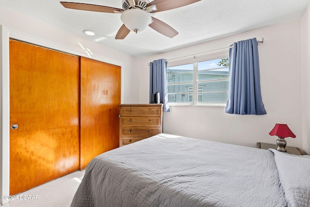 bedroom with ceiling fan, a textured ceiling, and a closet