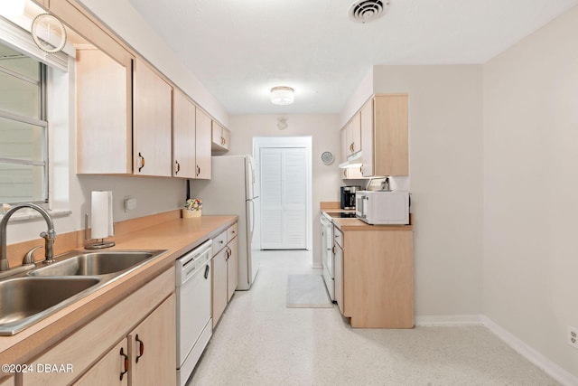 kitchen with light brown cabinets, white appliances, and sink