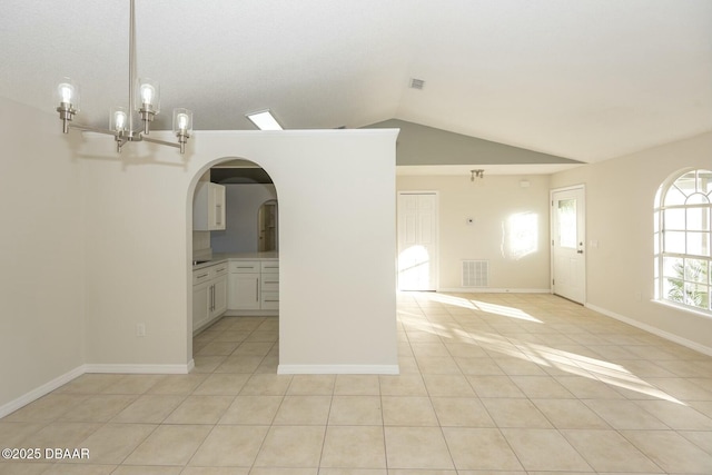 spare room featuring light tile patterned floors, an inviting chandelier, and vaulted ceiling