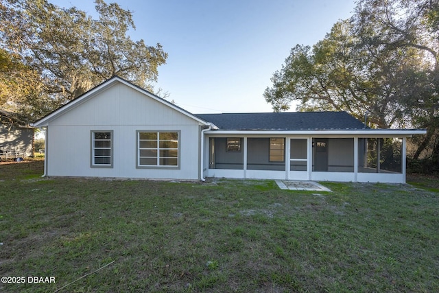 rear view of house featuring a sunroom and a lawn