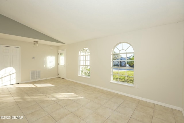 unfurnished room with light tile patterned floors and vaulted ceiling