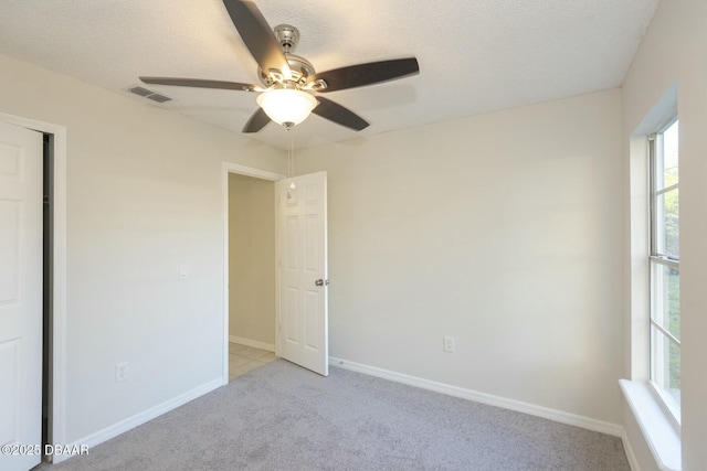 unfurnished bedroom featuring ceiling fan, light colored carpet, and a textured ceiling