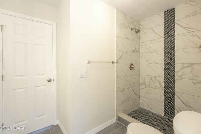 bathroom featuring a tile shower, tile patterned flooring, and toilet