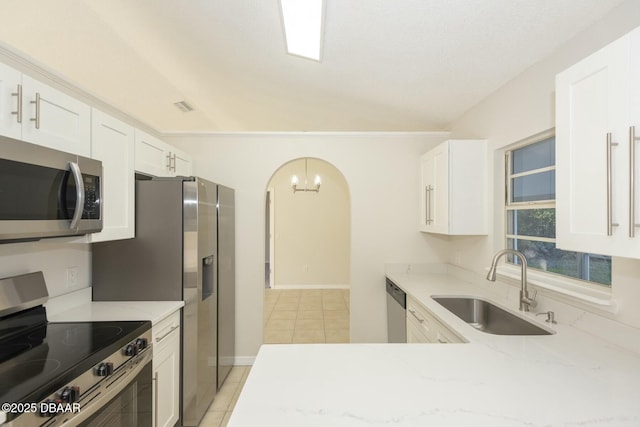 kitchen featuring white cabinets, sink, light stone countertops, appliances with stainless steel finishes, and light tile patterned flooring